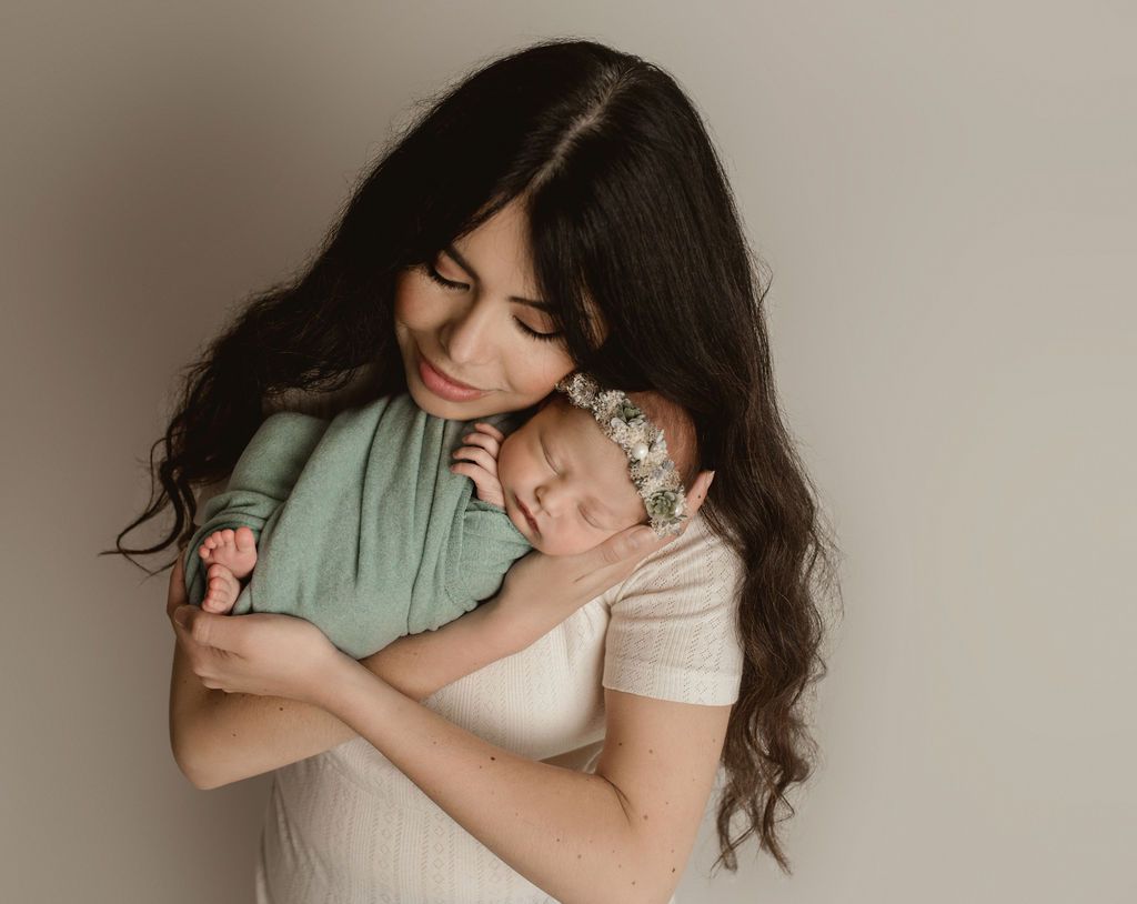 A woman is holding a newborn baby in her arms. Oregon Baby photographer near me