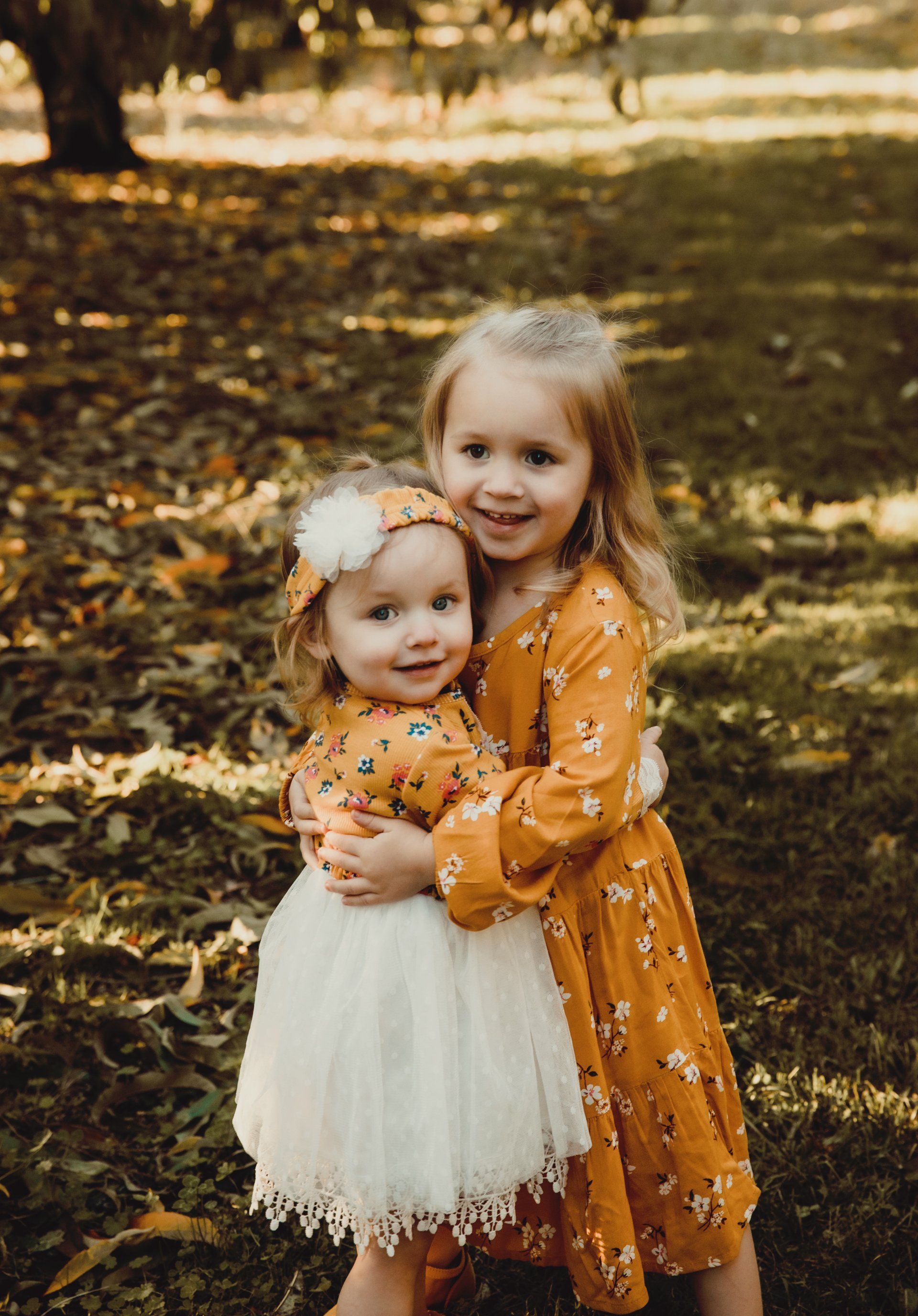 Two little girls are hugging each other in a park. Family photography