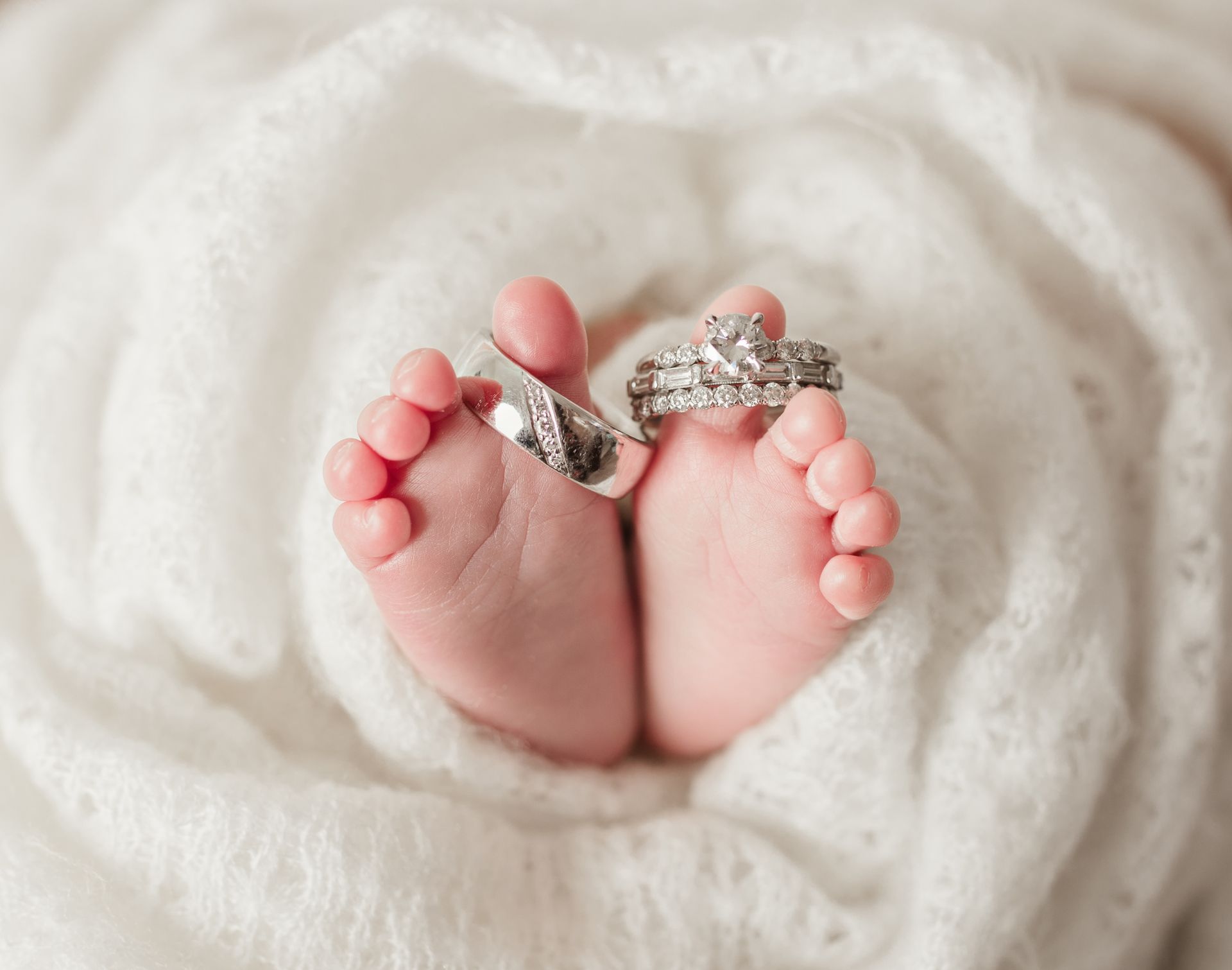 A baby 's feet with wedding rings on them.