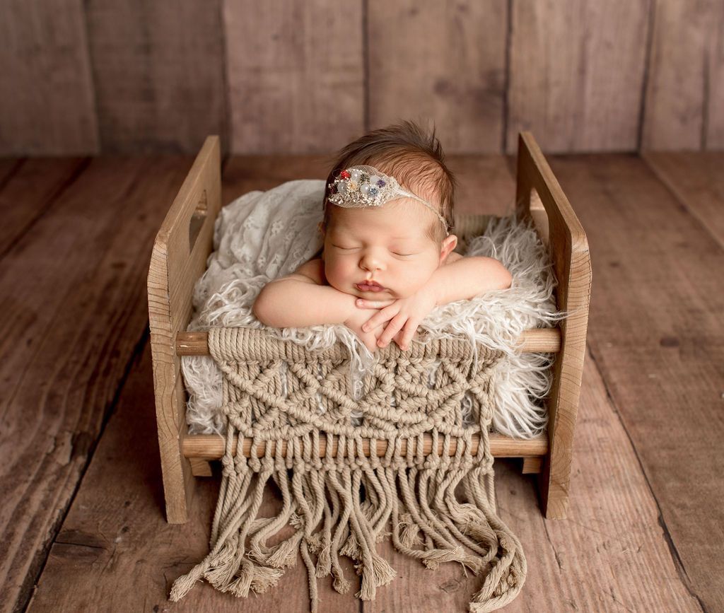 A newborn baby is sleeping in a wooden bed. Oregon newborn photographer near me