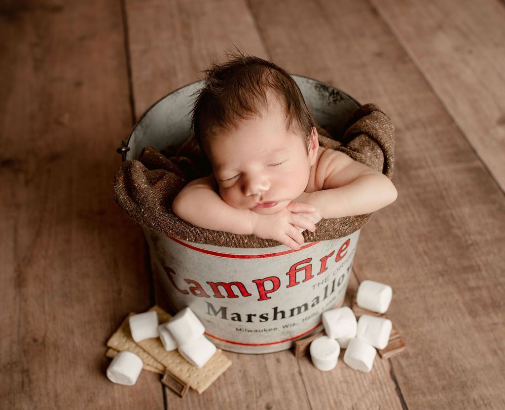 A baby is sleeping in a bucket of campfire marshmallows.