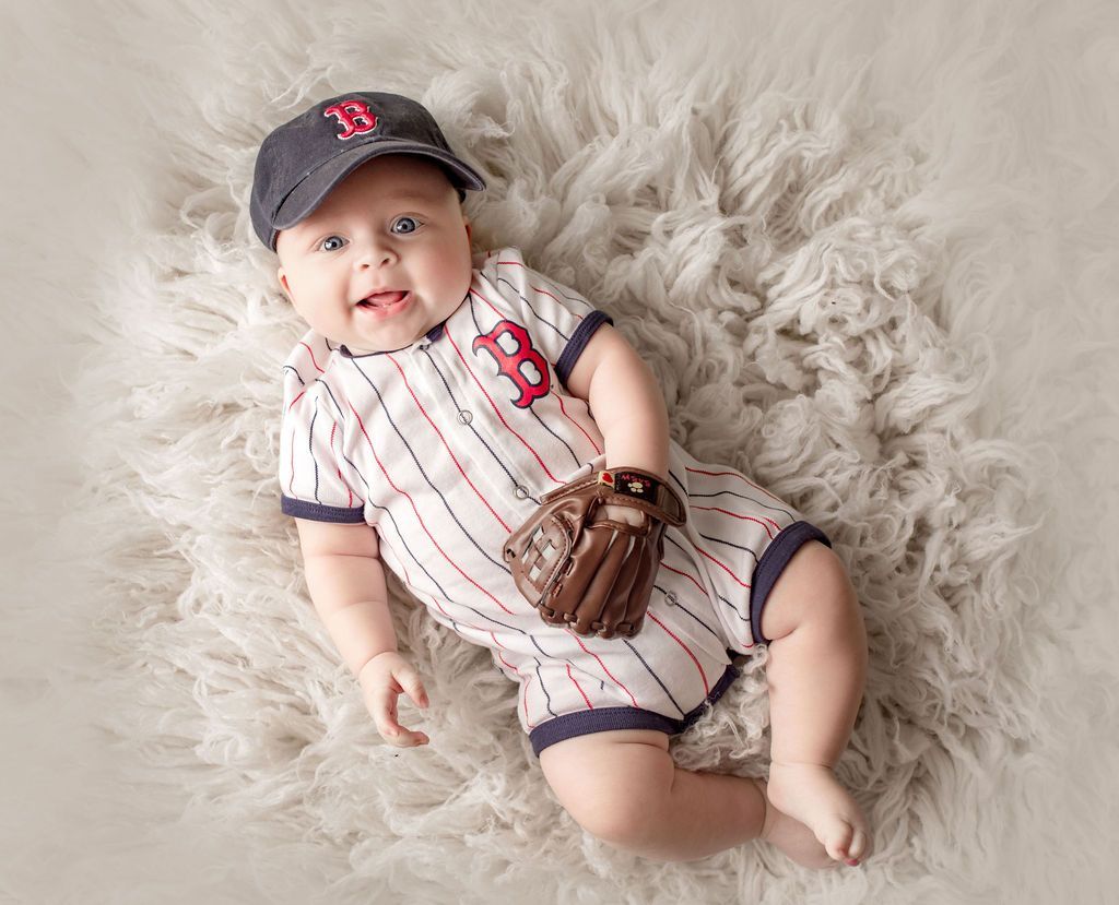 A baby is wearing a baseball uniform and holding a baseball glove.
