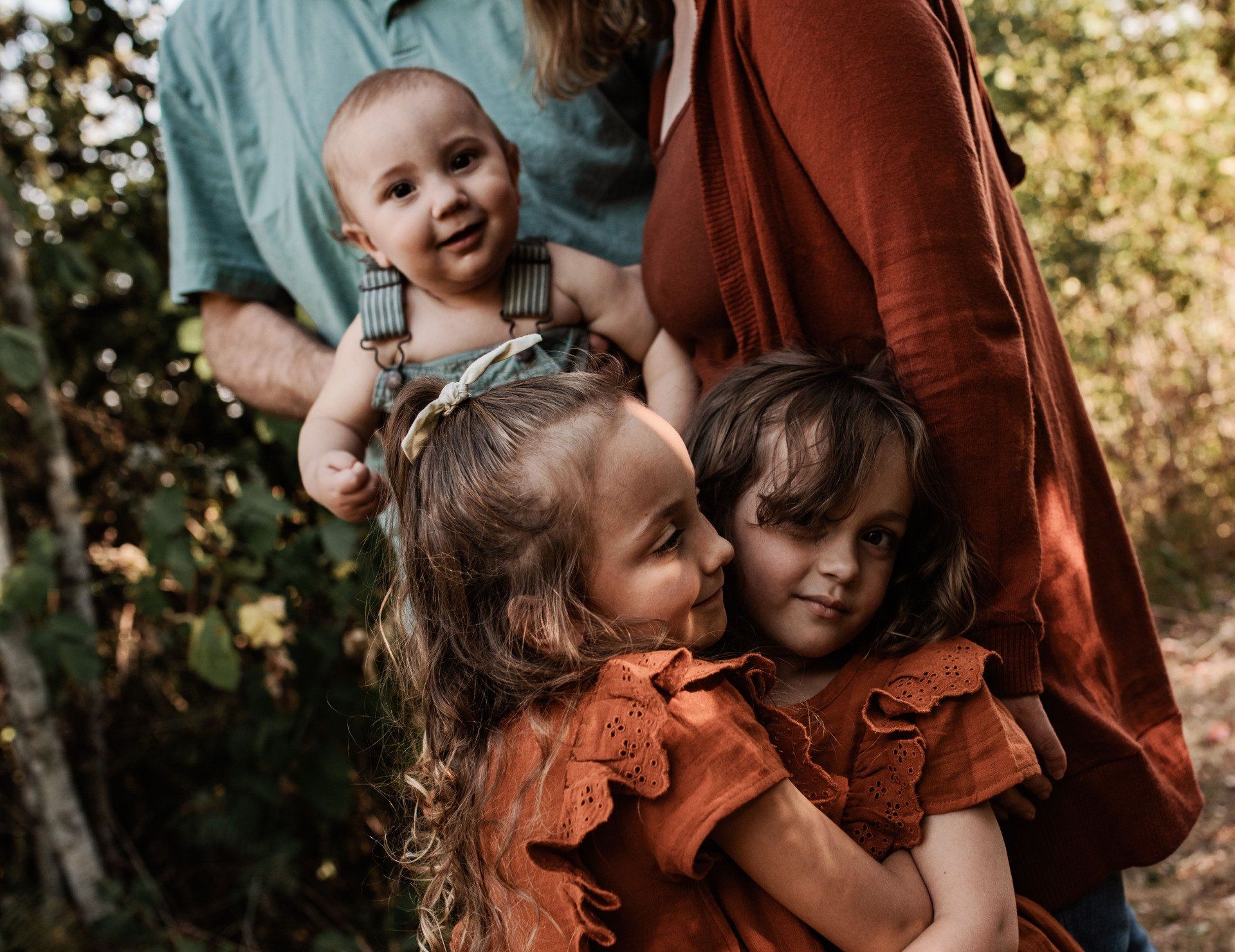 A woman is holding a baby and two little girls.