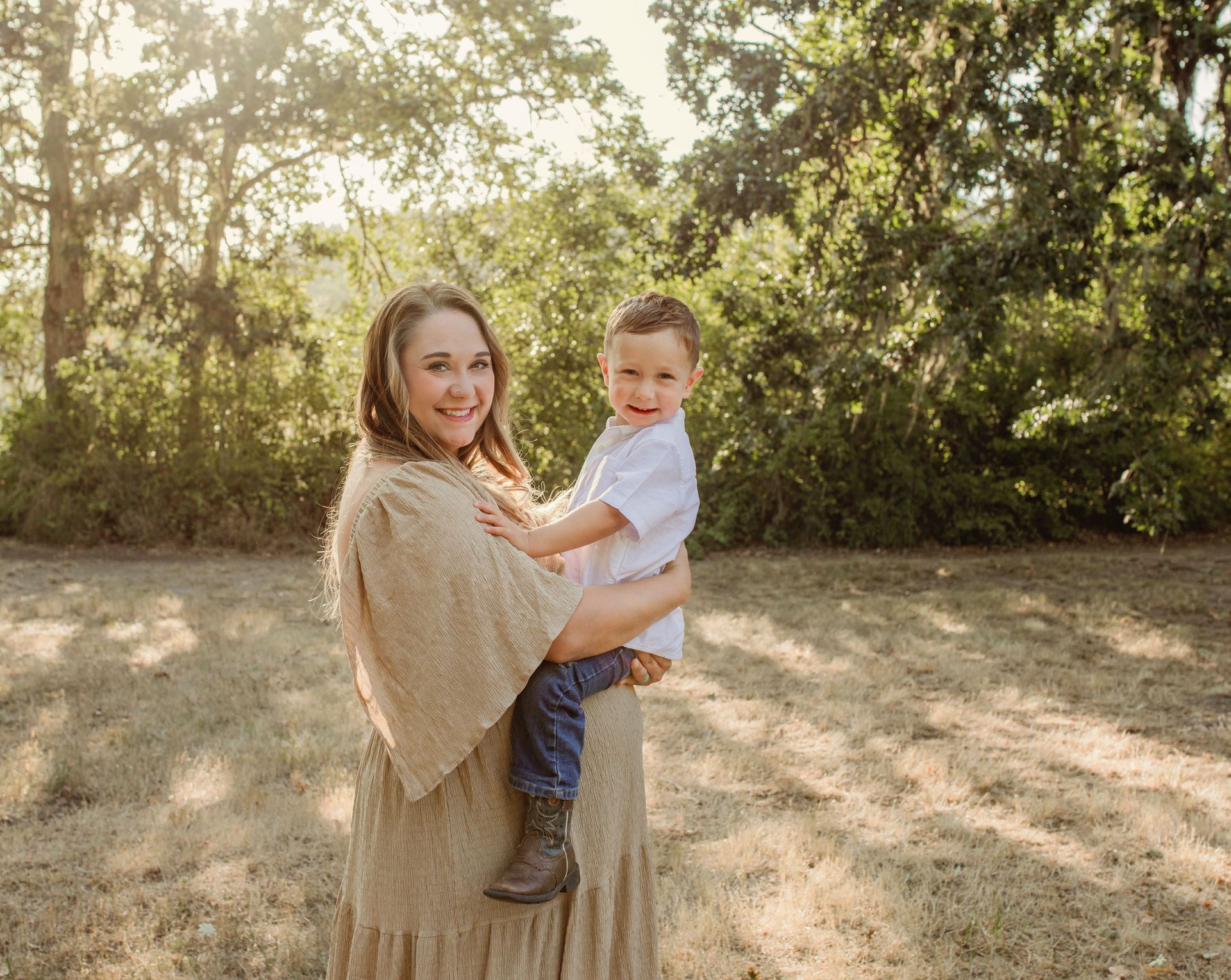 A woman is holding a little boy in her arms in a field.