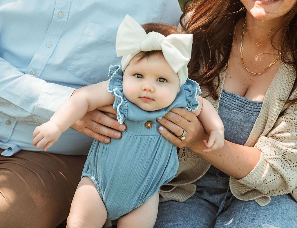A woman and a man are holding a baby in their arms.