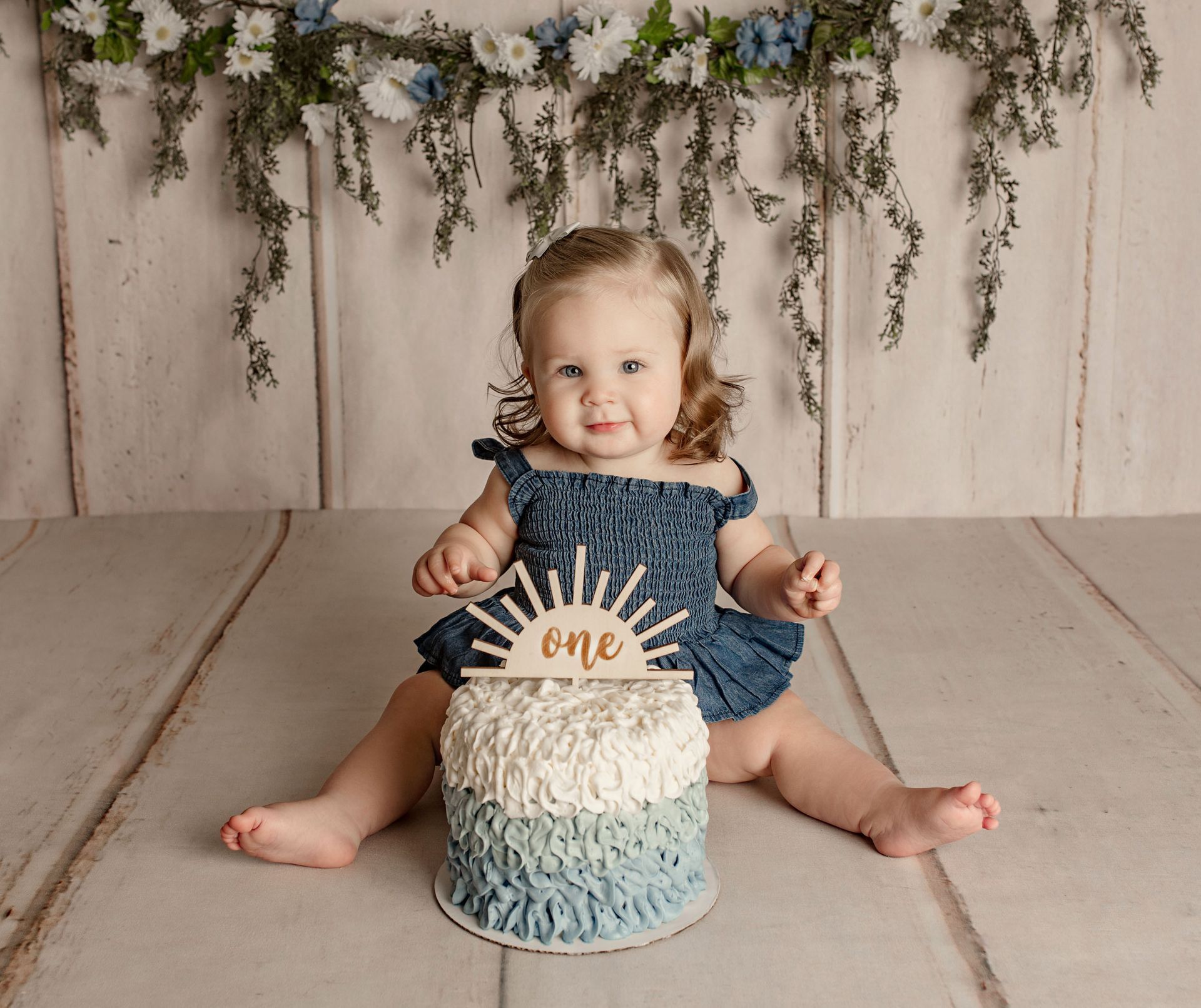 A baby is sitting in a wooden basket surrounded by sunflowers.