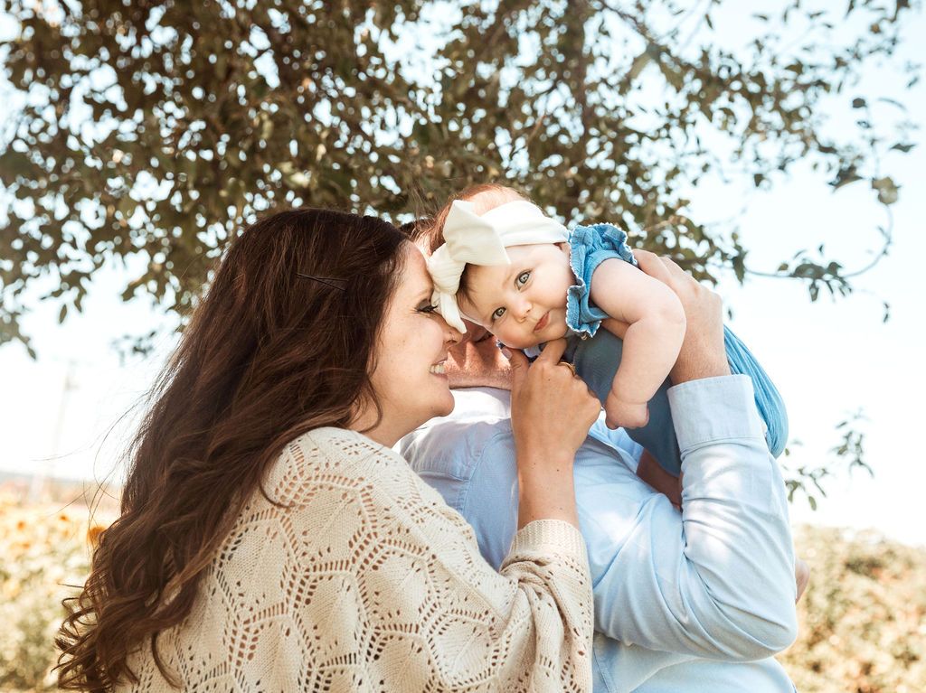 A woman and a man are holding a baby in their arms.