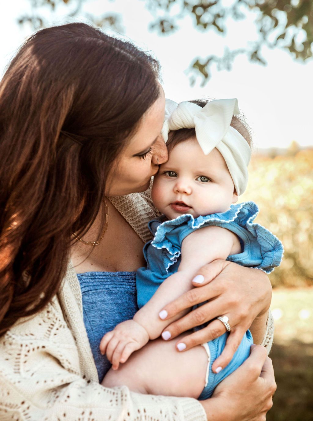A woman is holding a baby in her arms and kissing it on the cheek.