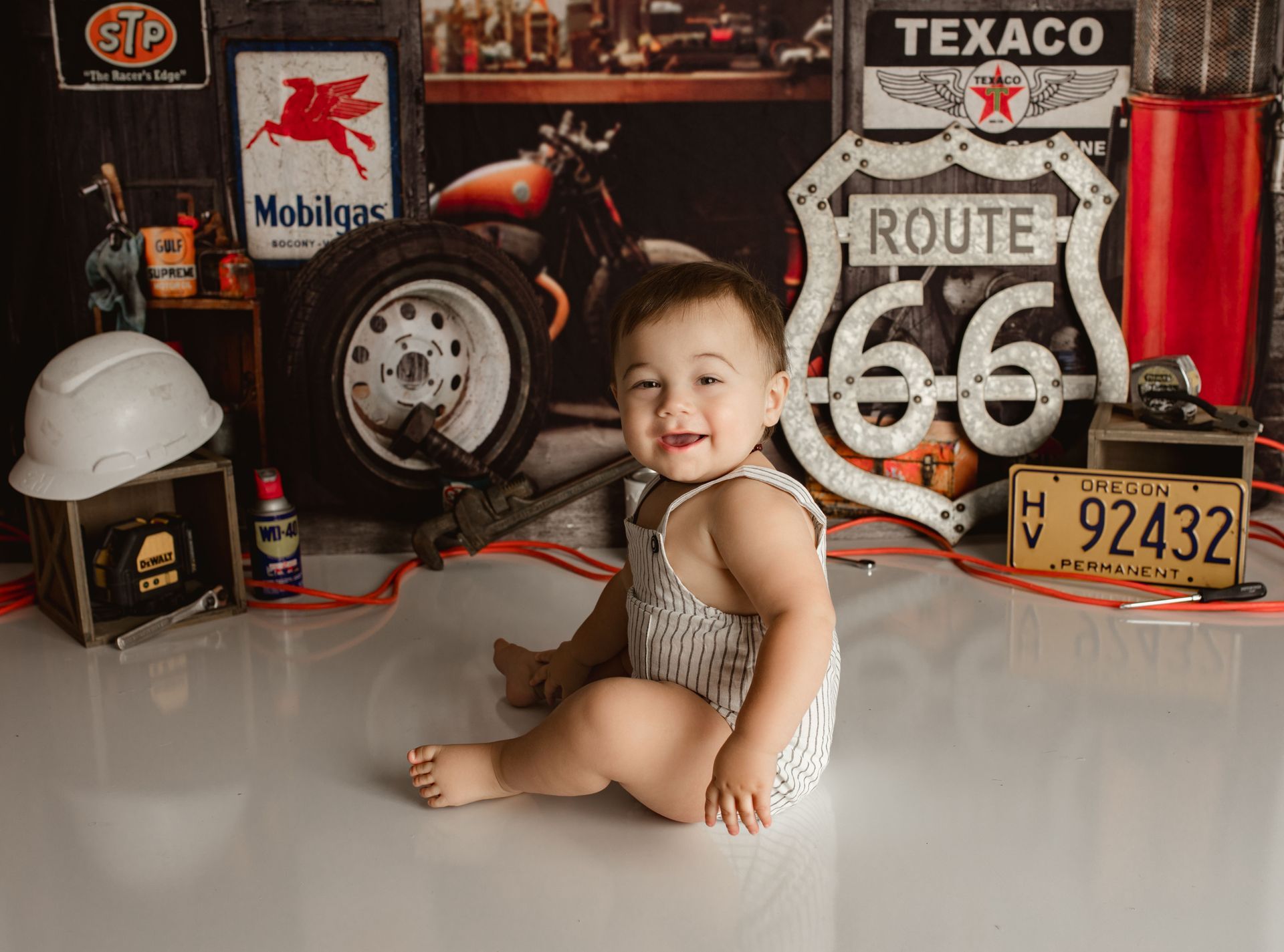 A baby is sitting on the floor in front of a route 66 sign. Oregon baby photographer