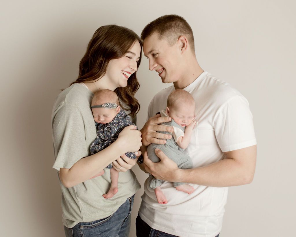 A man and a woman are holding two babies in their arms.