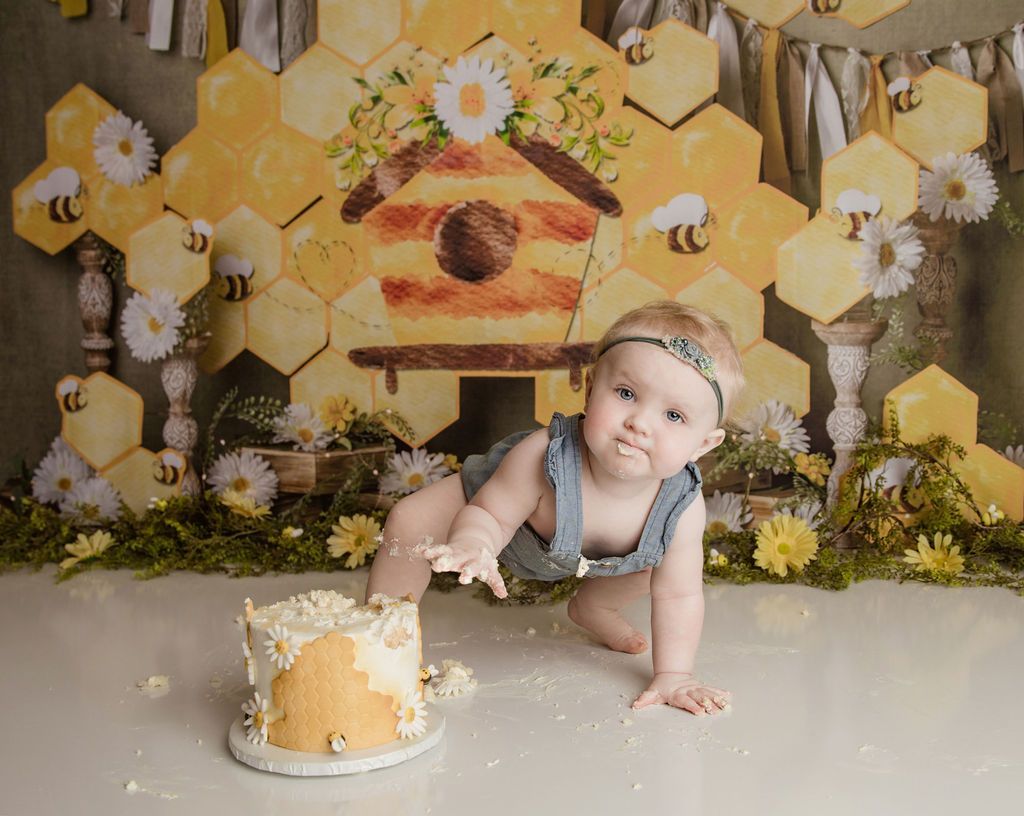 A baby is crawling on the floor next to a cake.