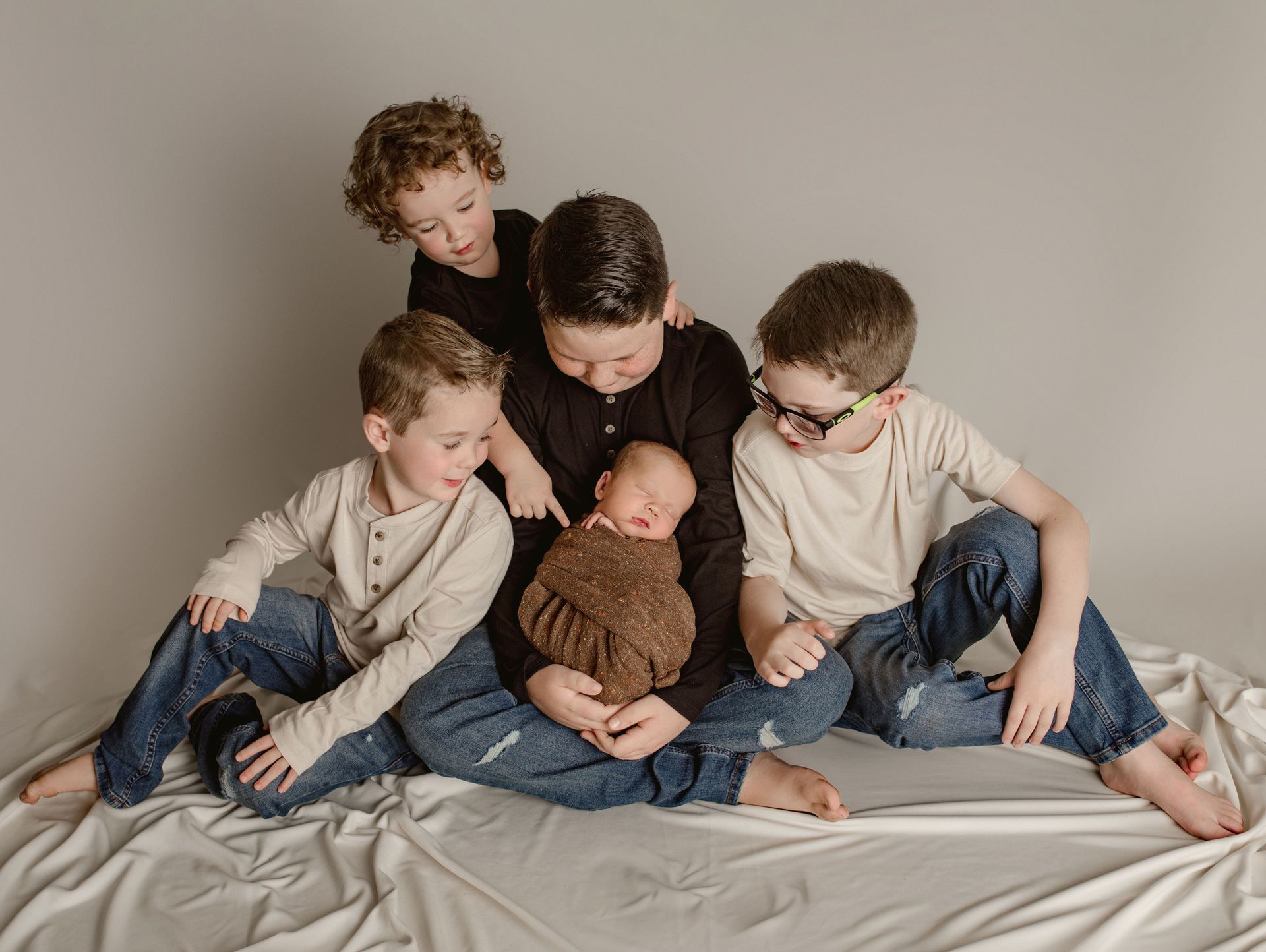 A group of young boys are sitting around a newborn baby.