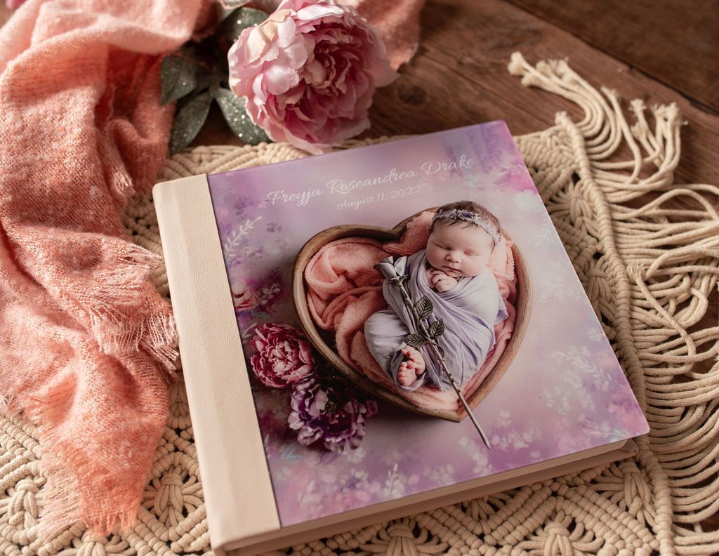 A baby is sleeping in a heart shaped bowl on a wooden table.