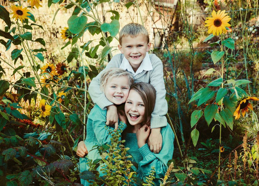 A group of children are posing for a picture in a field of sunflowers.