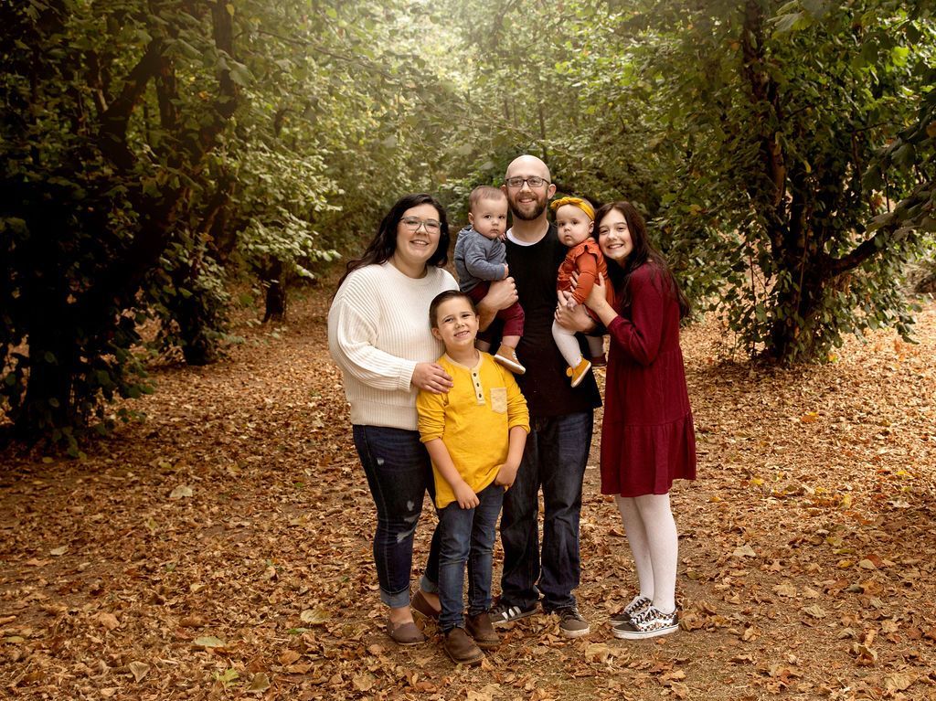 A family is posing for a picture in a forest.