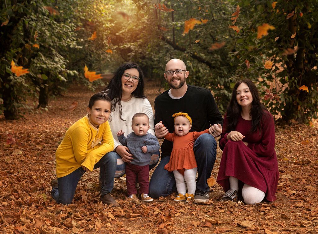 A family is posing for a picture in the leaves.