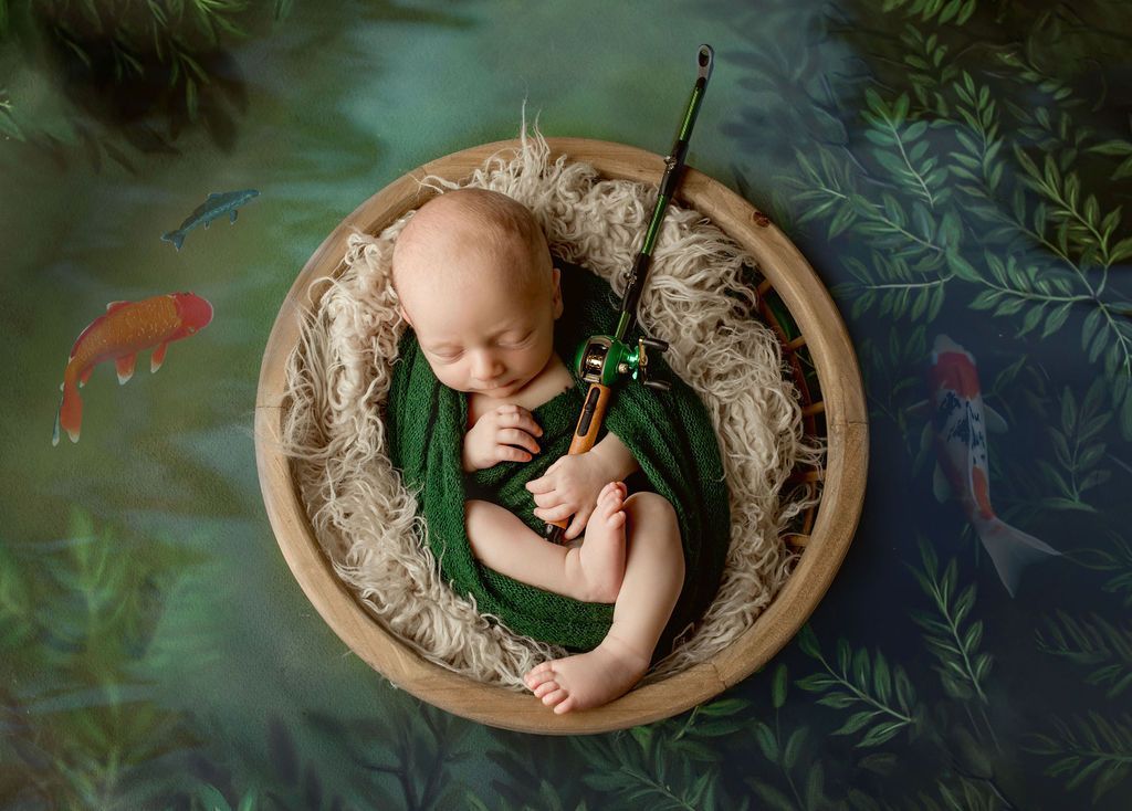 A newborn baby is sleeping in a wooden bowl with a fishing rod.