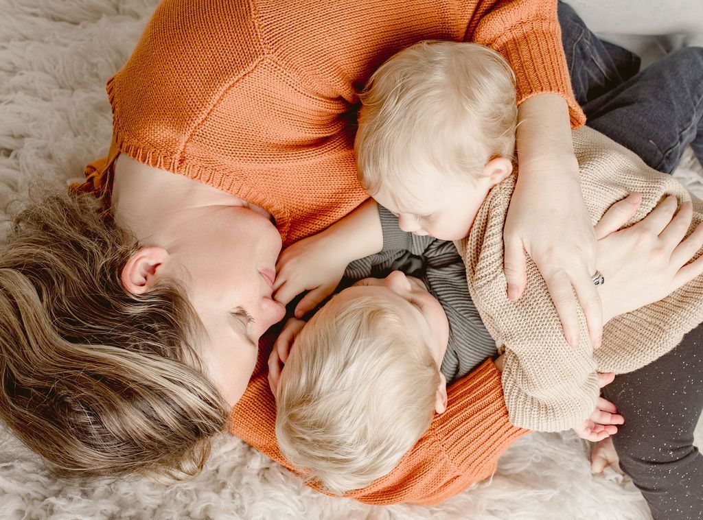 A woman is laying on the floor with two children.