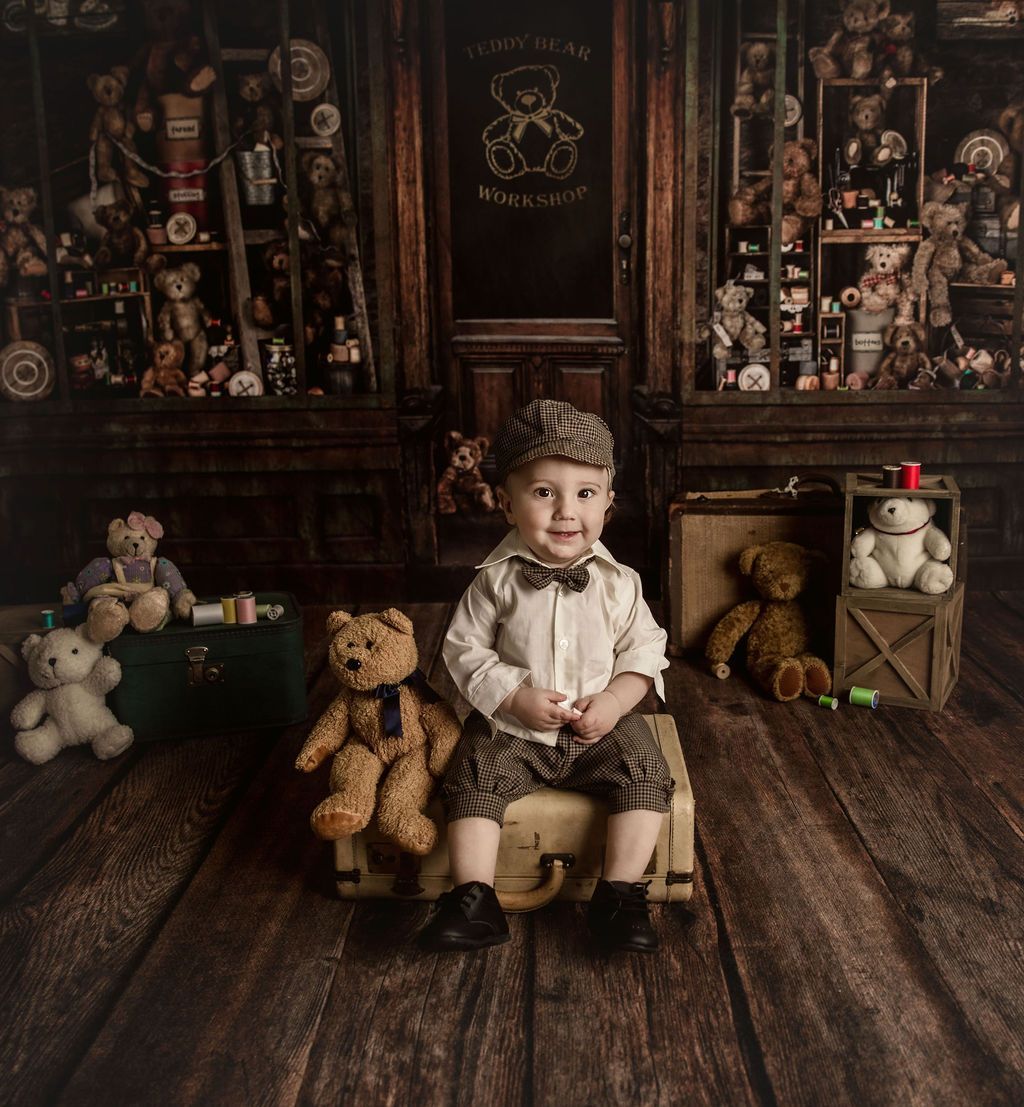 A little boy is sitting on a suitcase next to a teddy bear.