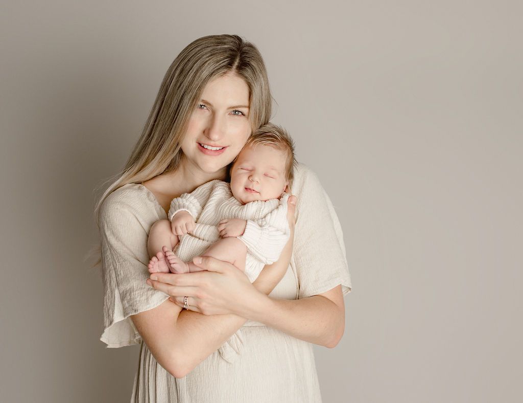 A woman is holding a newborn baby in her arms. Mom and Baby Poses Photos