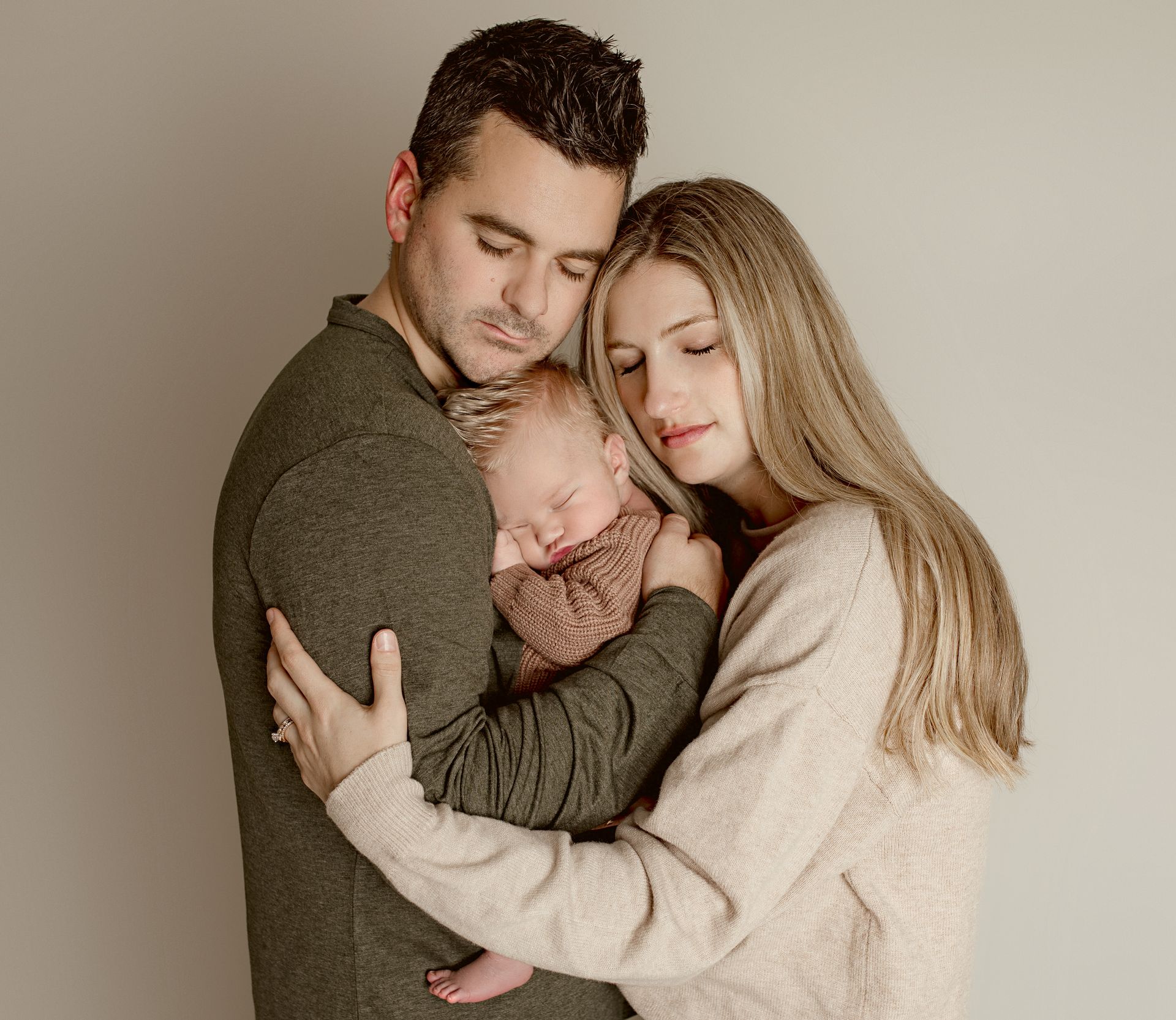 A man and woman are holding a newborn baby in their arms.