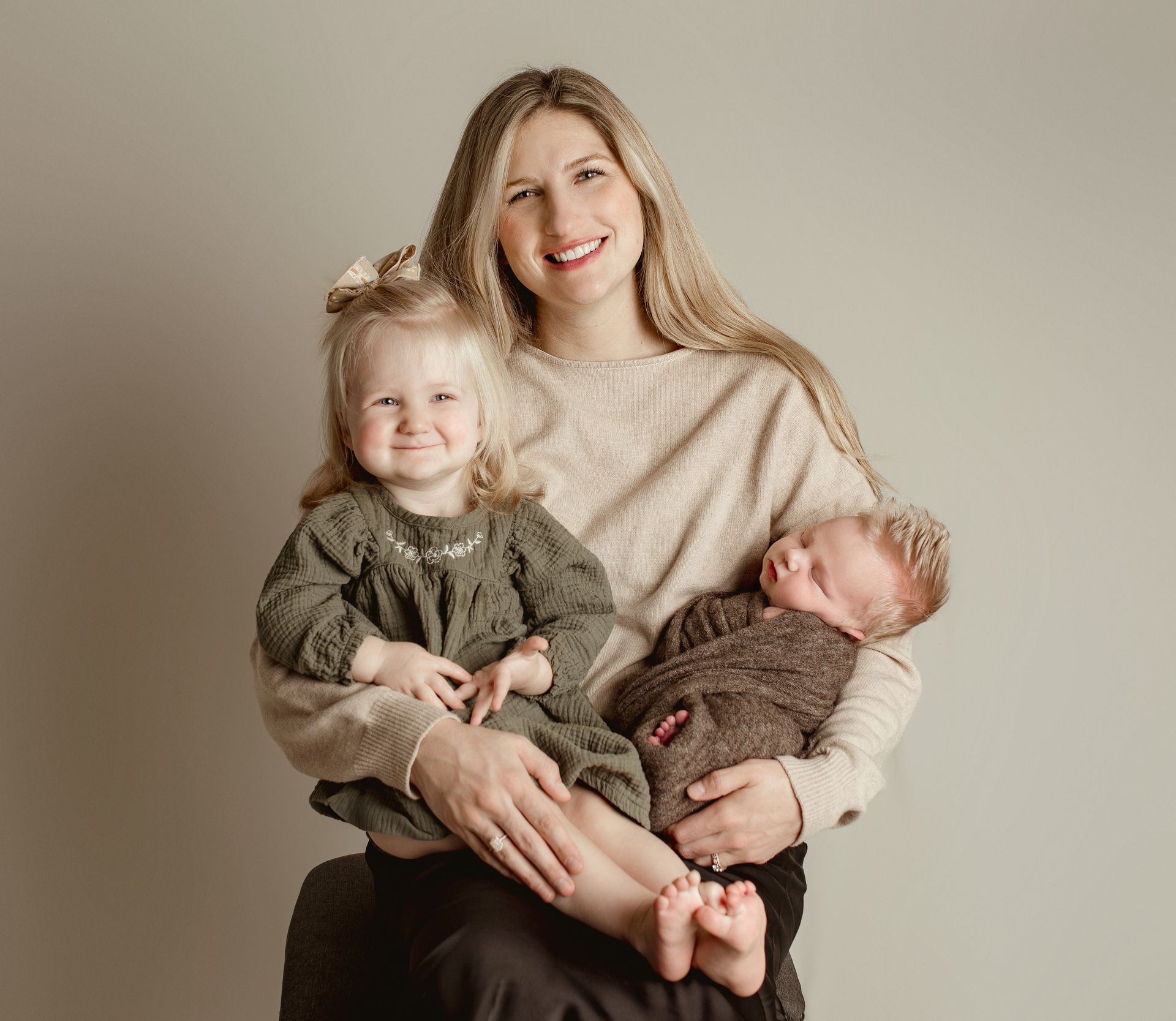 A woman is holding a baby and a little girl. Newborn motherhood photos