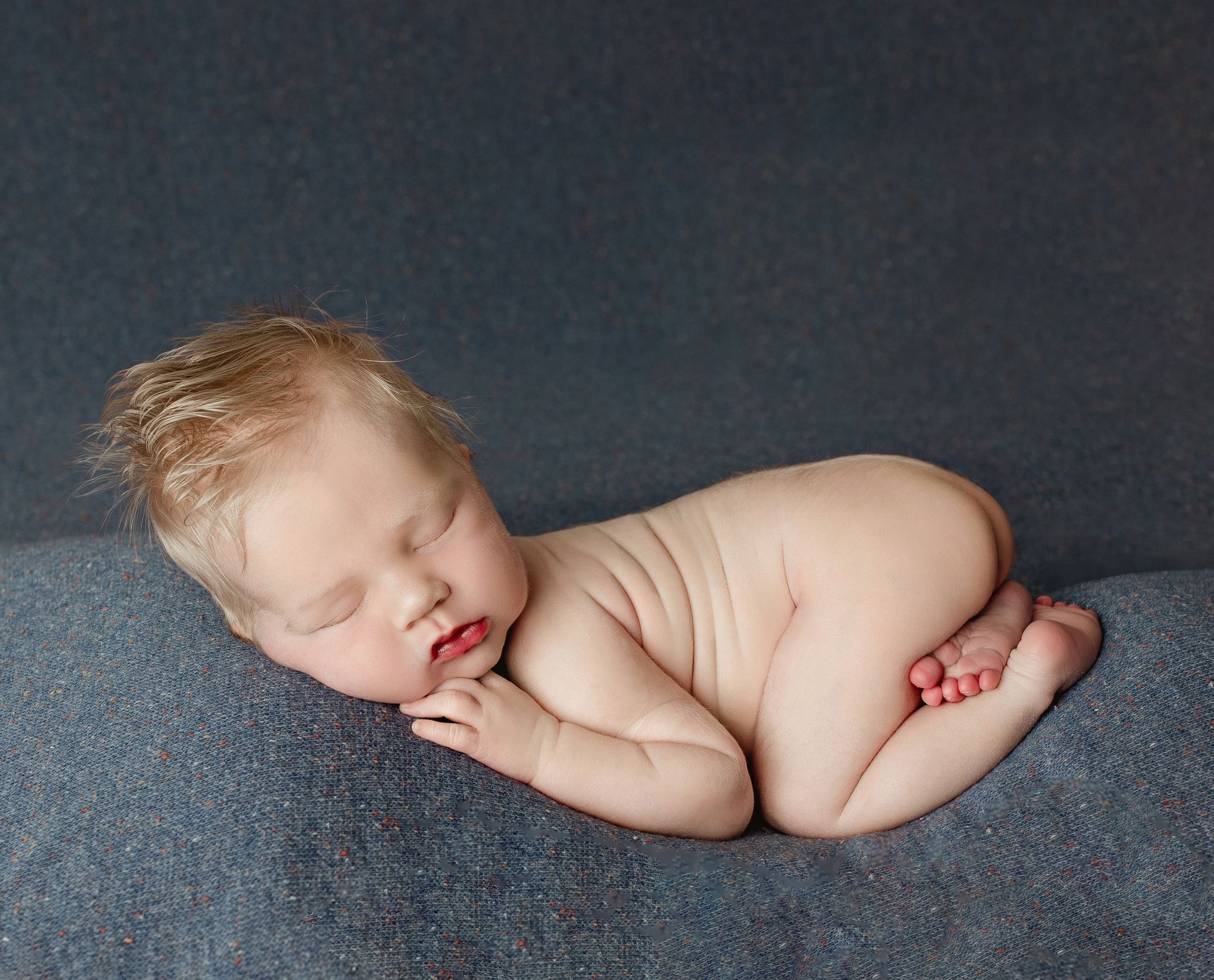 A newborn baby is sleeping on a blue blanket