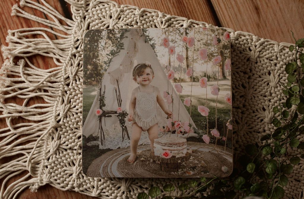 A picture of a baby sitting in a tent on a wooden table.
