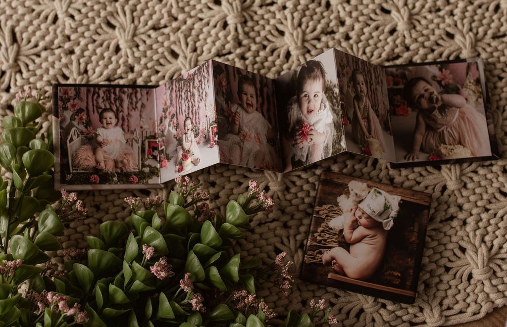 A book filled with pictures of a baby is sitting on top of a knitted blanket.