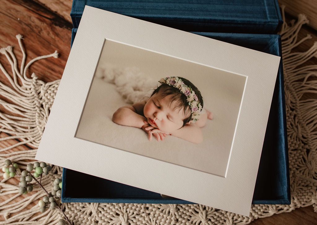 A picture of a baby in a blue box on a wooden table.