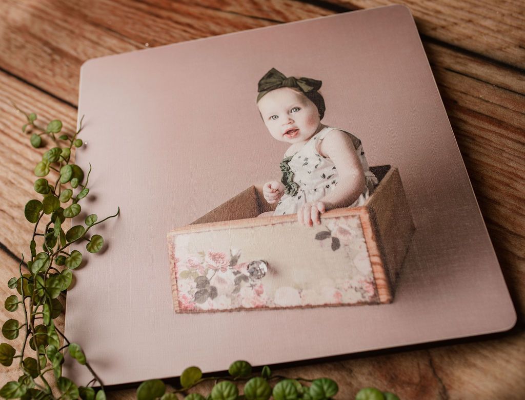 A baby is sitting in a wooden box on a wooden table.