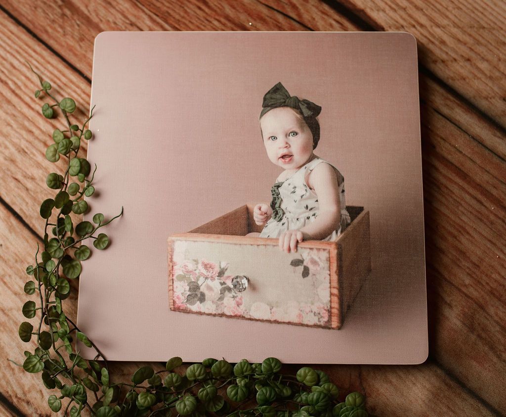 A baby is sitting in a wooden box on a wooden table.