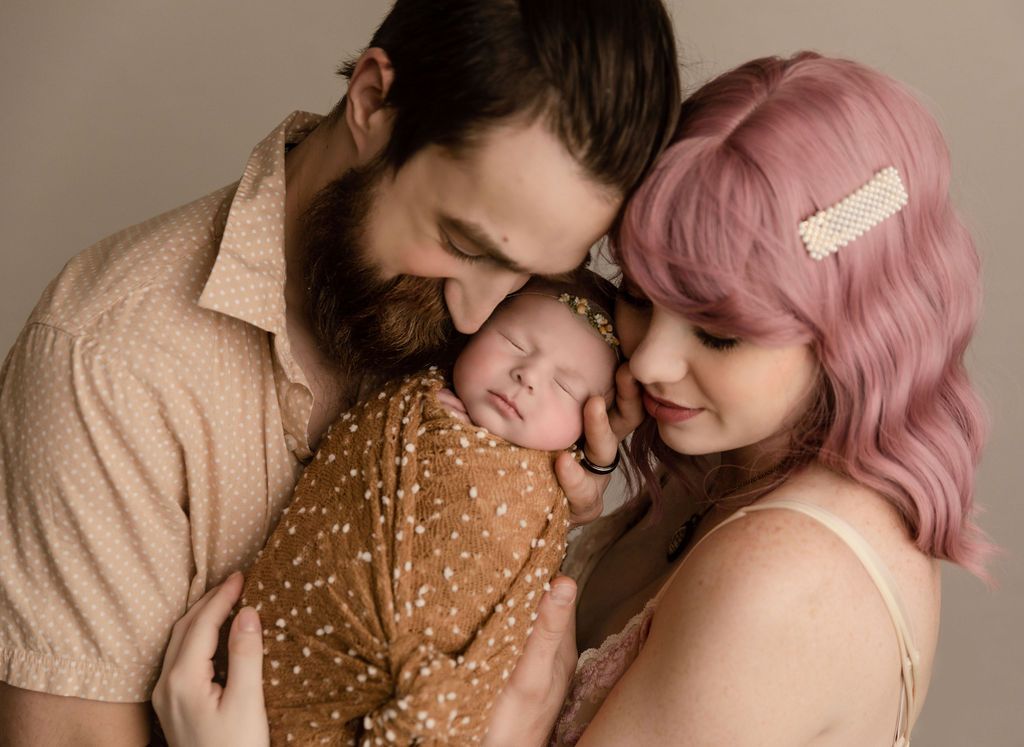 A man and a woman are holding a newborn baby.