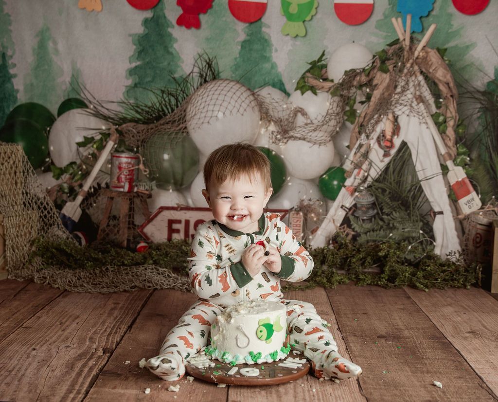 A baby is sitting on a wooden floor eating a cake.