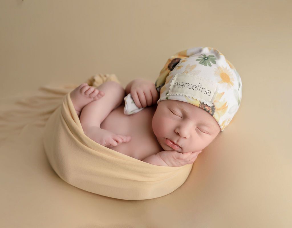 A newborn baby is wrapped in a blanket and wearing a hat.