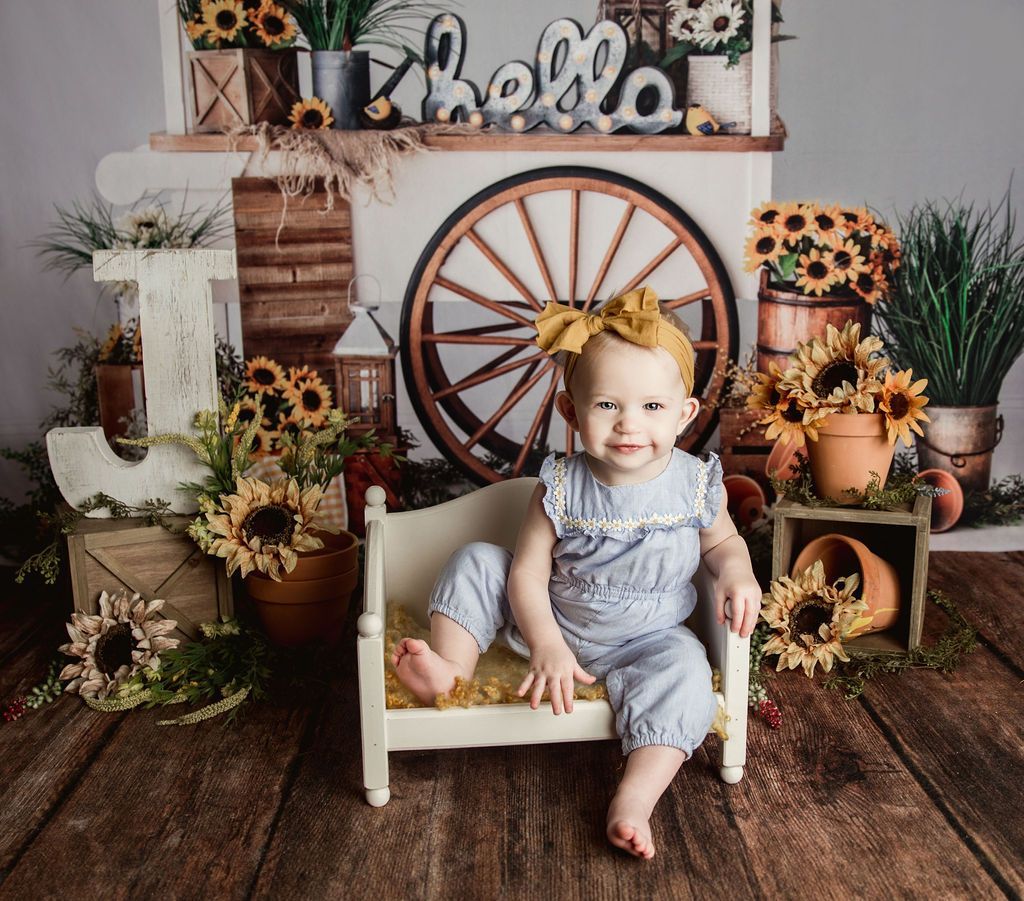 A baby girl is sitting in a small bed in front of a sign that says hello.