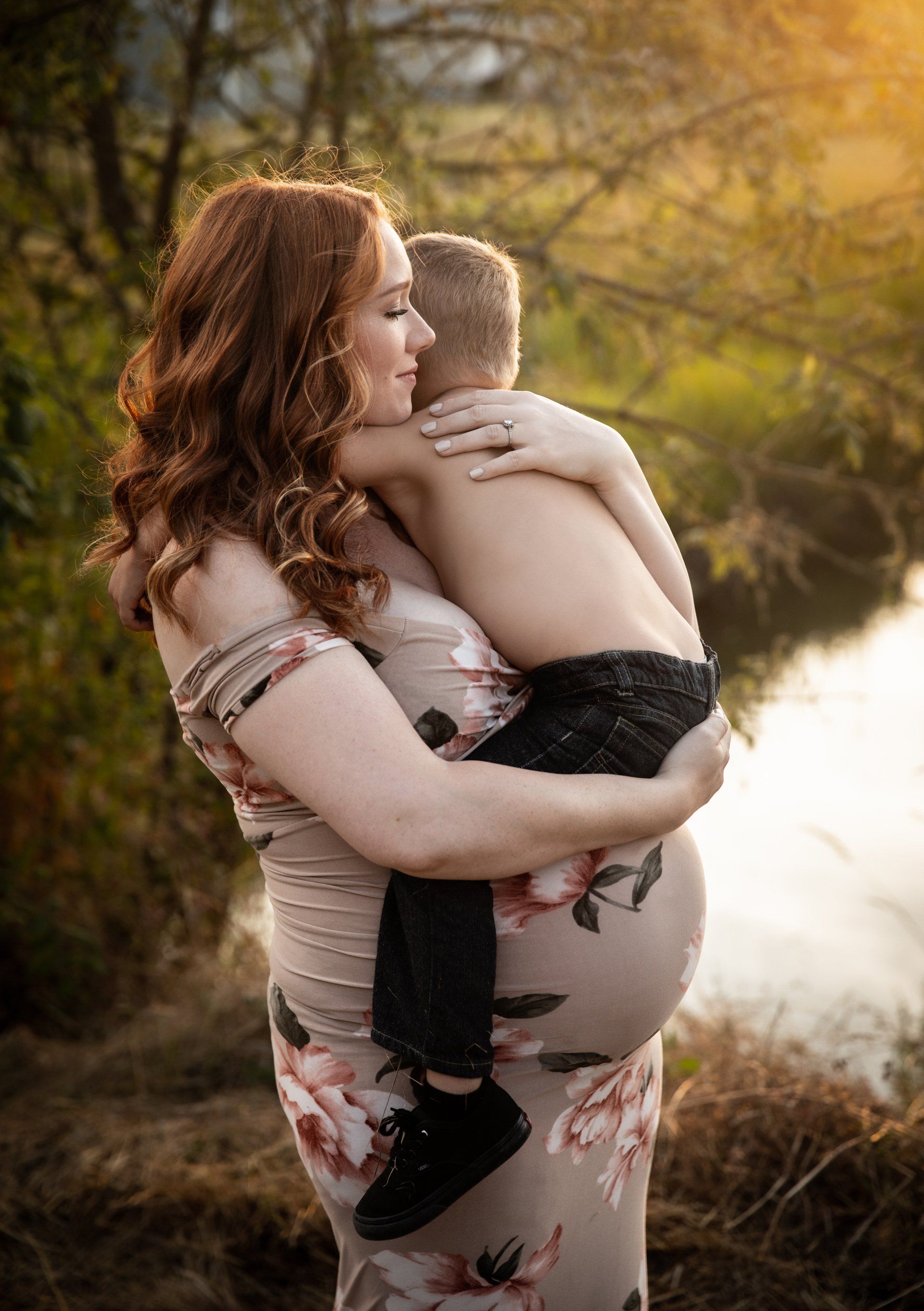 A pregnant woman is holding a little boy in her arms. Photographers that have studios