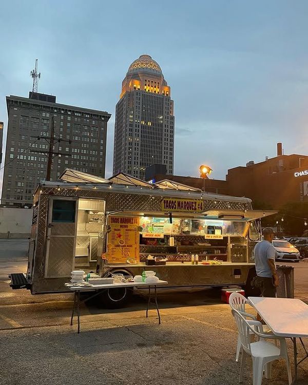 A food truck is parked in front of a tall building.