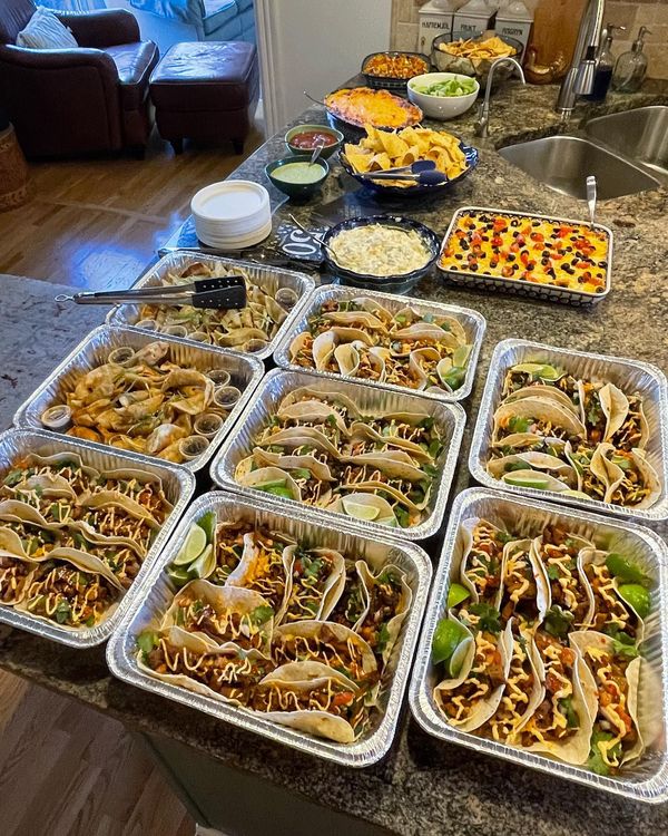 A bunch of trays of food are sitting on a counter.