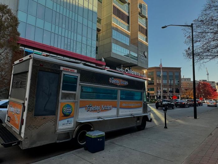 A food truck is parked on the side of the road in front of a building.