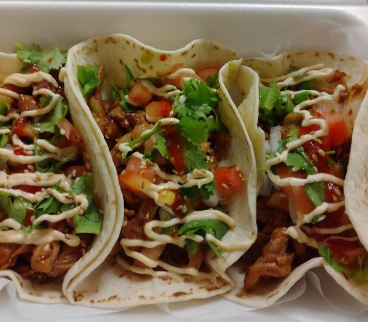 A tray of tacos with lettuce tomatoes and mayonnaise