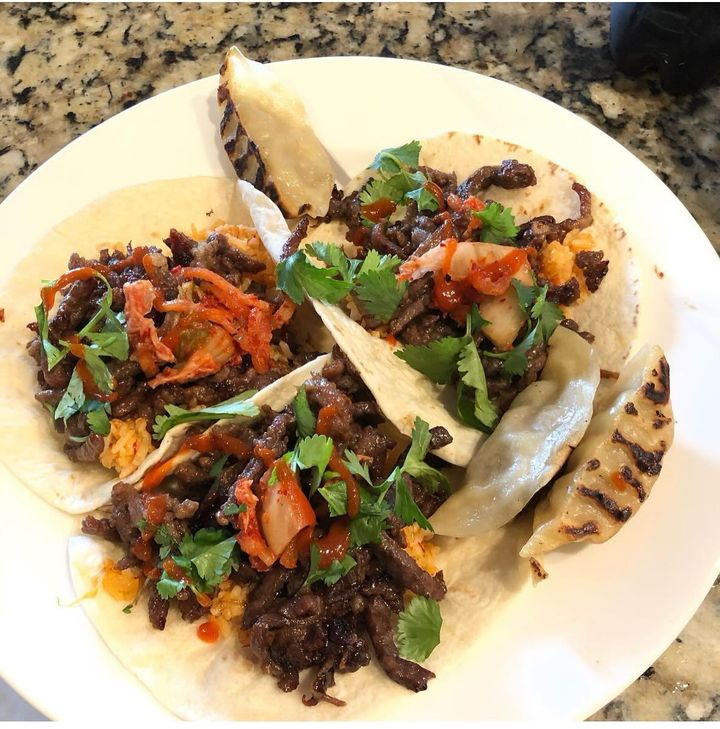 A white plate topped with three tacos with meat and vegetables