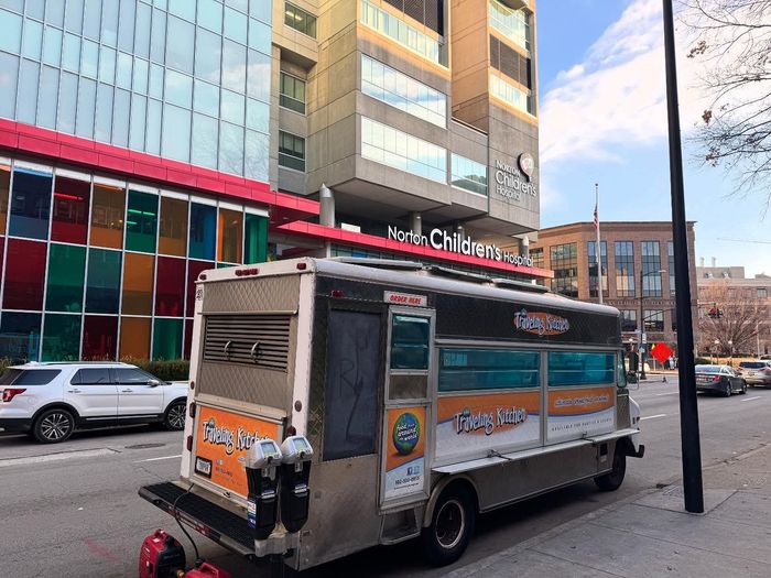 A food truck is parked on the side of the road in front of a building.