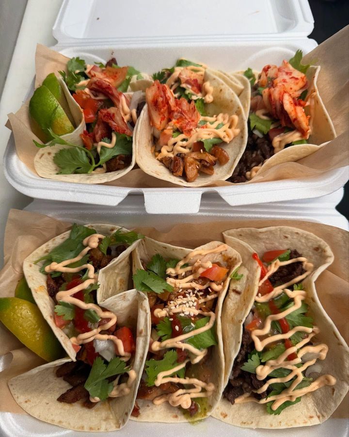 Two styrofoam containers filled with tacos on a table.