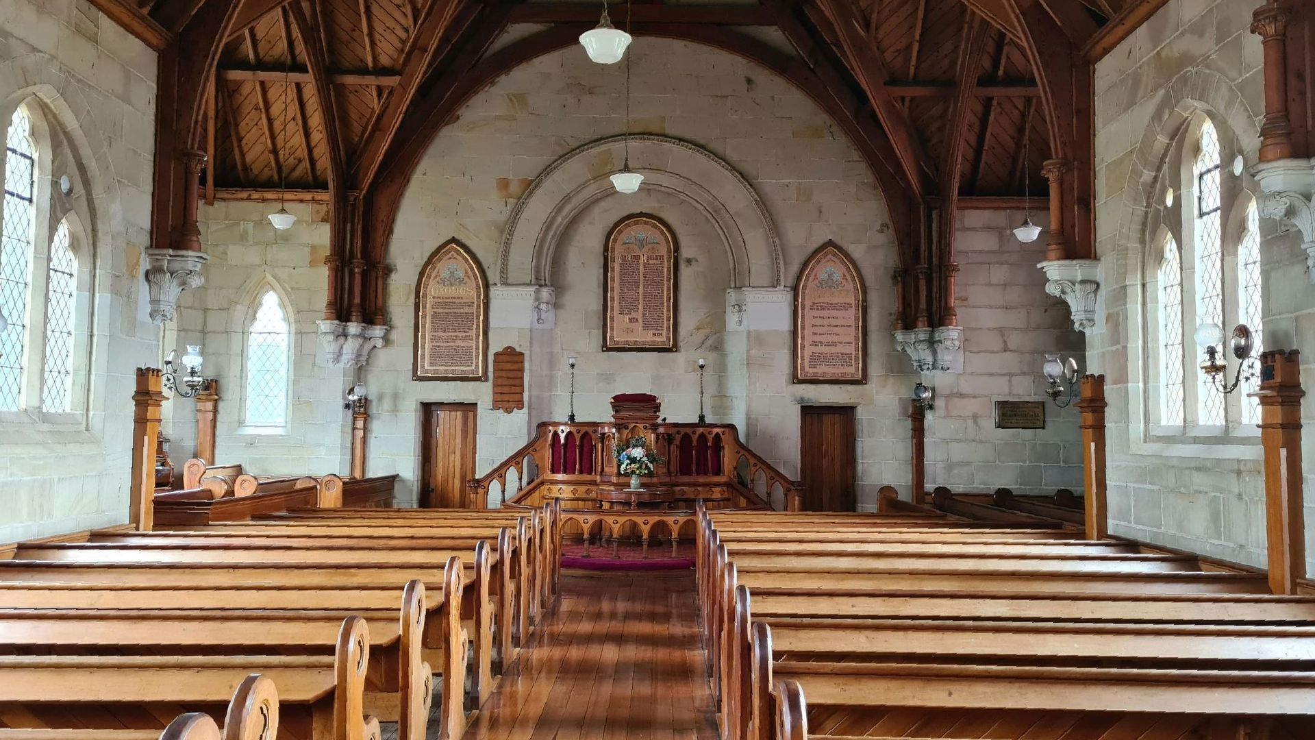 Interior of a church with wooden pews, high arched ceiling, and ornate wooden beams.