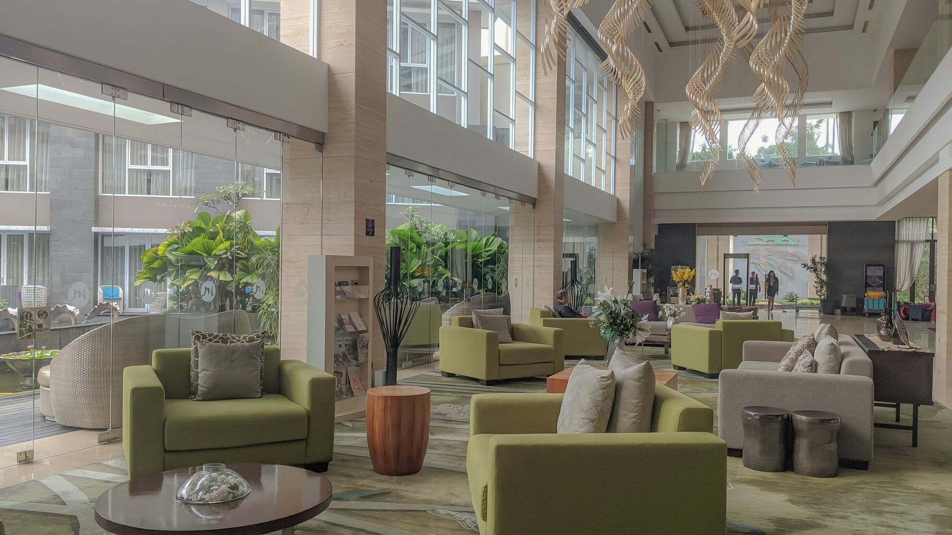 Lobby with seating, large windows, and an outdoor view. Green and neutral-toned furniture.