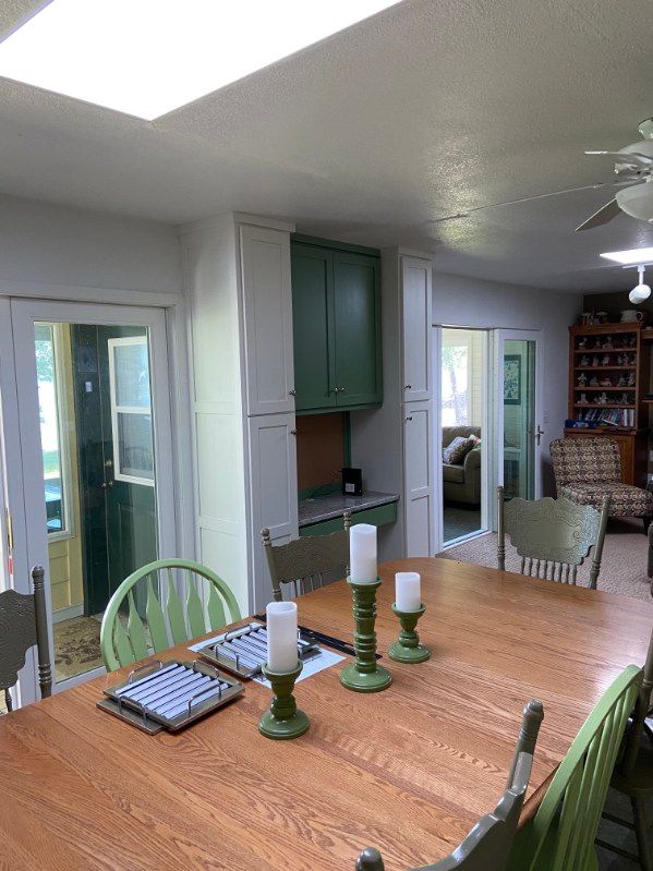 Dining room with wooden table, green chairs, and green cabinets.