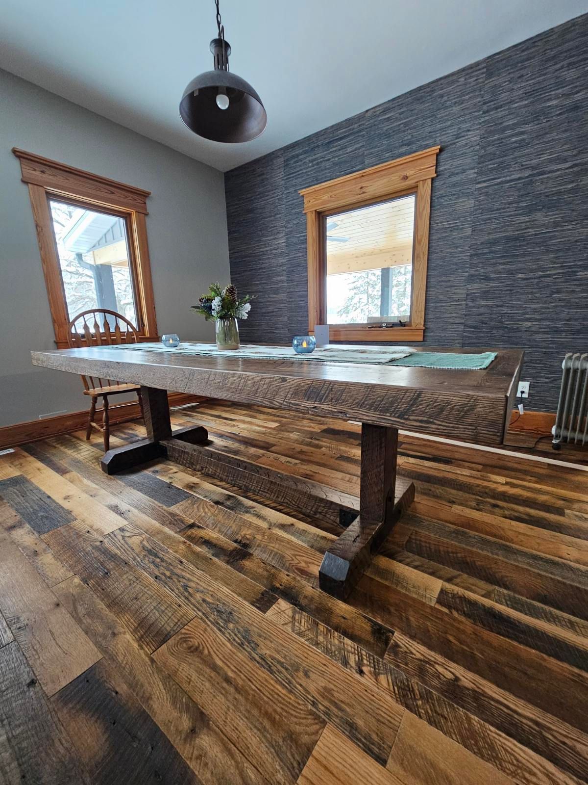 Rustic wooden dining table with black metal legs, set in a room with hardwood floors and textured wall.
