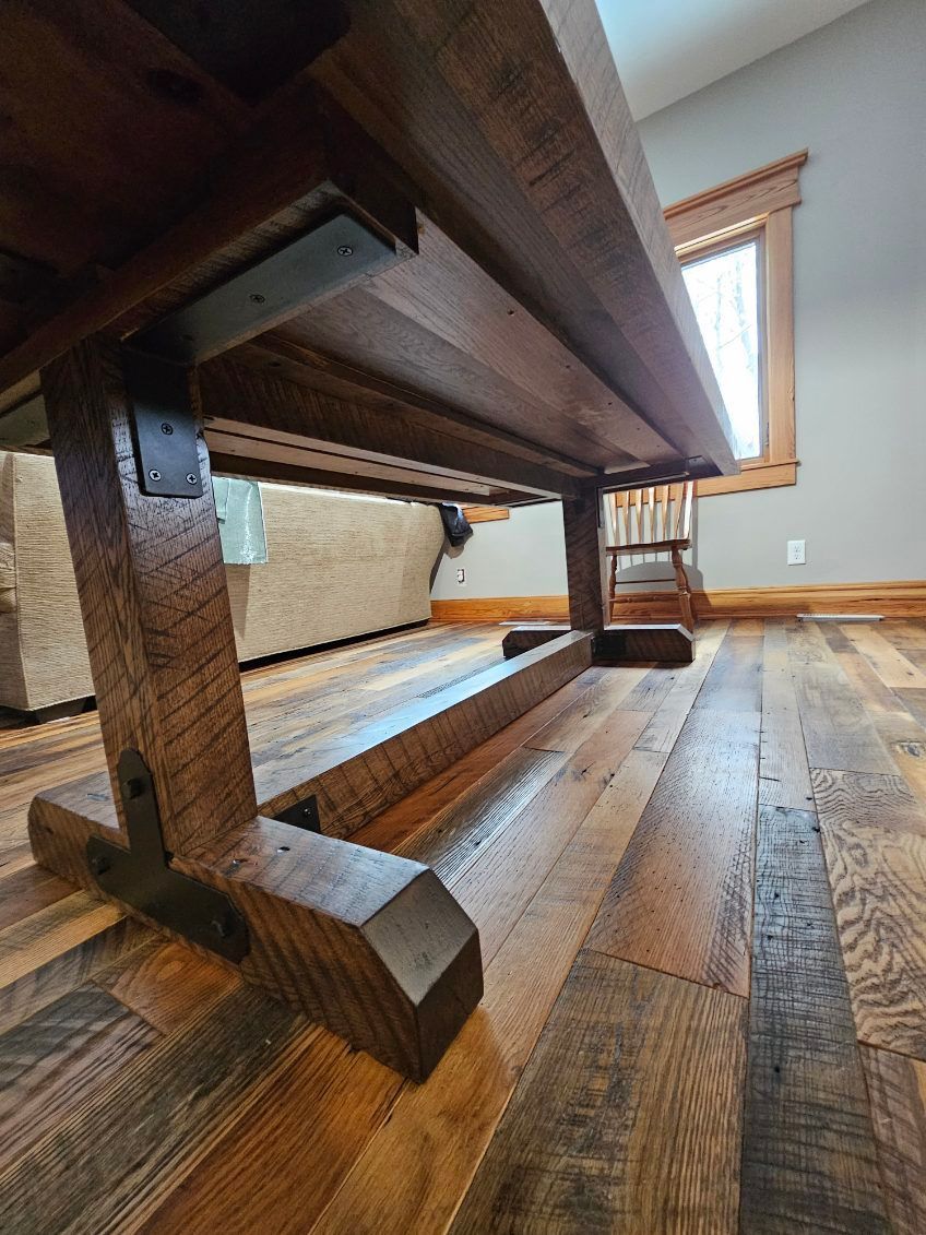 Wooden trestle table with dark wood construction on wood floor.