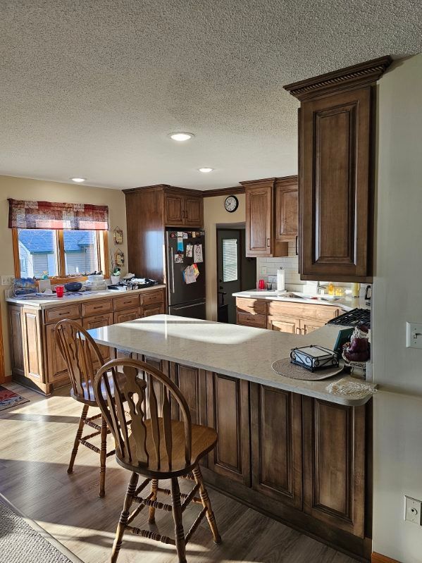 Kitchen with wooden cabinets, countertop bar, and two wooden stools.